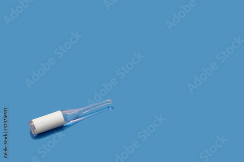 Glass ampoule with a liquid medicine on a blue background, there is a place to insert text.