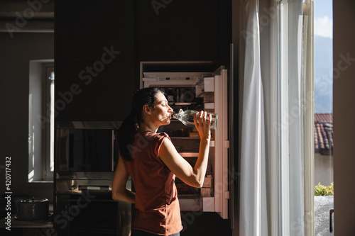 Woman drinking water after workout at home photo