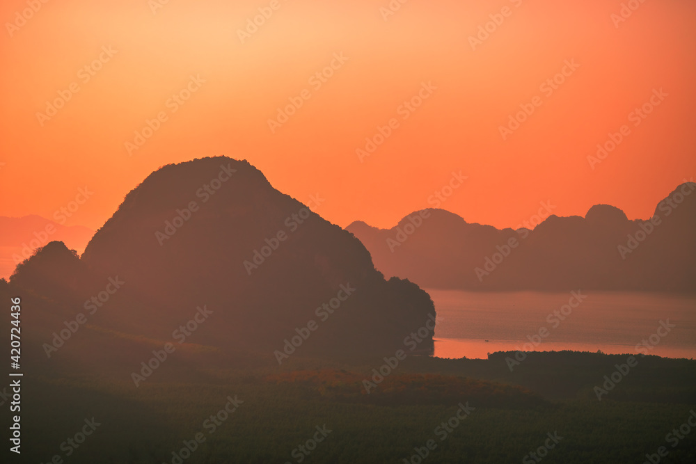 Obraz premium The natural background of the morning light rising in the middle of the sea and surrounded by mountains, cool breezes, the beauty of the ecology of the tourist attractions.