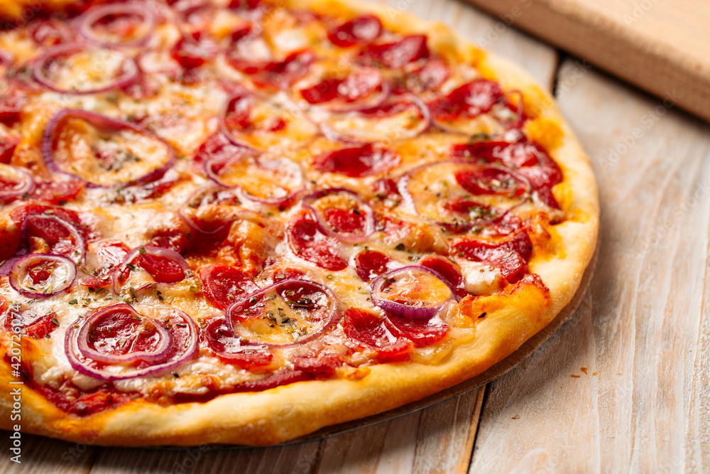 Closeup on hot spicy sausage pizza with onion on the wooden background