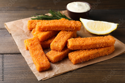 Fresh breaded fish fingers served on wooden table