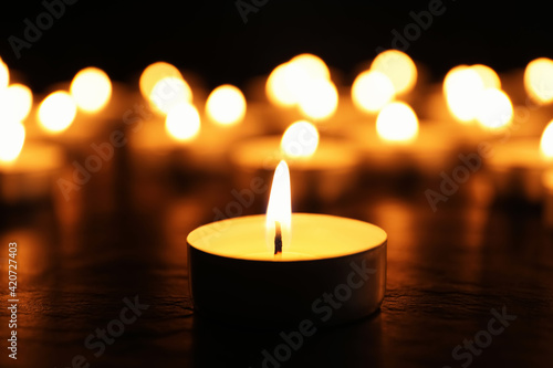 Burning candle on black table, closeup. Memory day