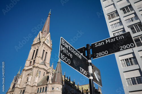 Signpost with street names at intersection of Bartolome Mitre and San Martin streets in Mar del Plata, Argentina. Cathedral Church called Basilica Catedral de los Santos Pedro y Cecilia on background.