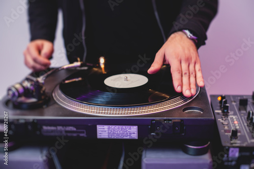 View of Dj mixer and vinyl plate with headphones on a table with DJ playing and mixes the track in the background, during night techno party in the nightclub