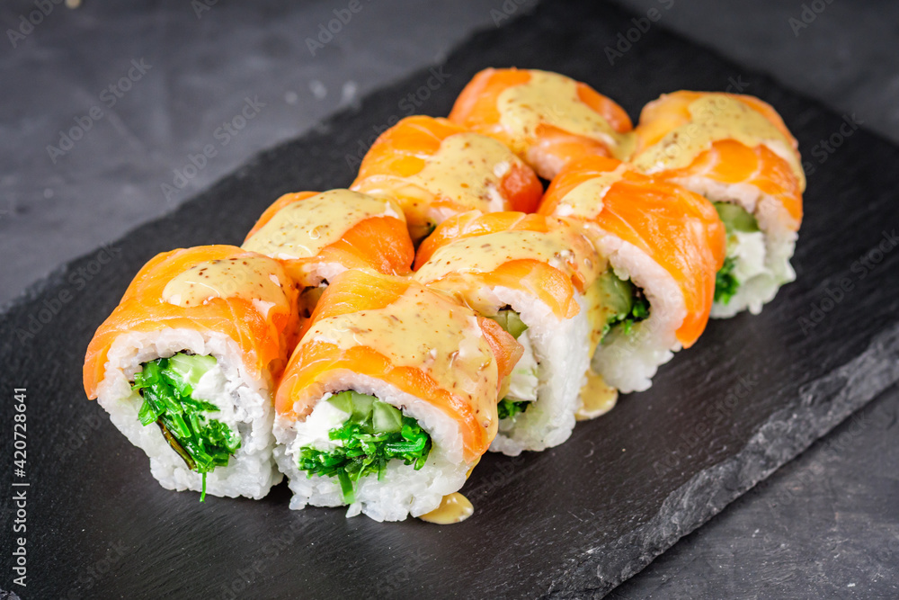 appetizing sushi roll philadelphia with salmon cucumber and chuka on a black stone plate appetizing sushi roll philadelphia with salmon cucumber and chuka on a black stone plate