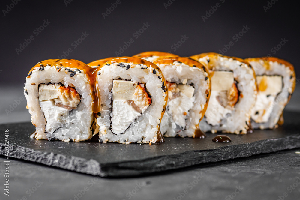 appetizing sushi roll california with eel tofu sesame and unagi cheese on a black stone plate appetizing sushi roll california with eel tofu sesame and unagi cheese on a black stone plate