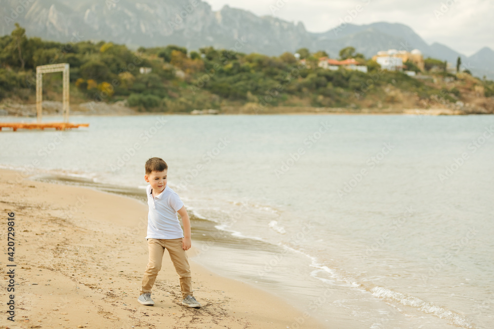 Little boy plays on the beach . Child at Mediterranean Sea in Turkey and Cyprus. Vacation with family and small children 