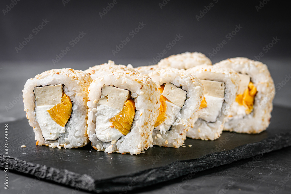 appetizing sushi roll california with tofu cheese and omelet on a black stone plate appetizing sushi roll california with tofu cheese and omelet on a black stone plate