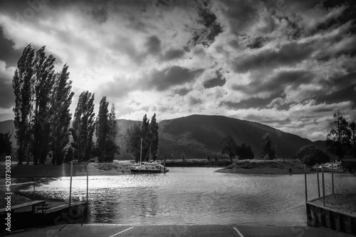 Scenic Landscape with backlit trees in black and white at Te Anau Boating Club Marina - view from the docks on the shore of Lake Te Anau in New Zealand, South Island.