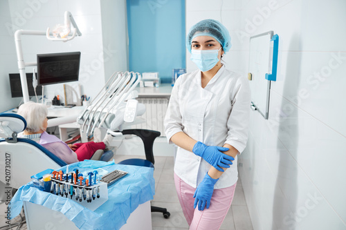 Dental professional with bouffant cap holding her arm