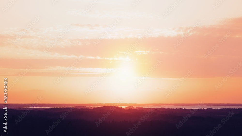 Amazing aerial view from a watchtower over the endless forest and lake at sunset. 16x9