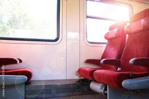 Empty seats in the modern high speed train. Red chairs in the train. Travel in the summer. Lens flare effect