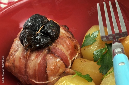 Paupiette de lapin aux pruneaux avec des pommes de terre et une fourchette servies dans une assiette en gros plan photo