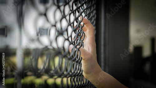 Slavery trade and trafficking victim concept of woman prisoner in jail being tortured, punished or abused in violation with hand holding cage wire mesh
