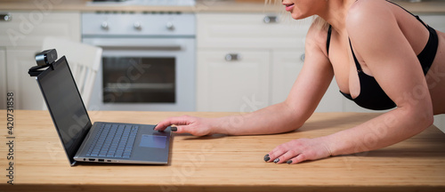 A girl in underwear flirts on an online video connection on a laptop. Woman working as a web cam model