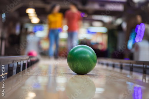 Young couple having fun in bowling alley. Focus is on bowler.