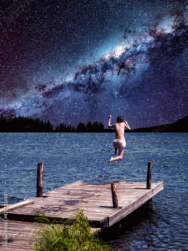 Surrealistic collage.Man dives into the water off the pier on the background of the Milky Way