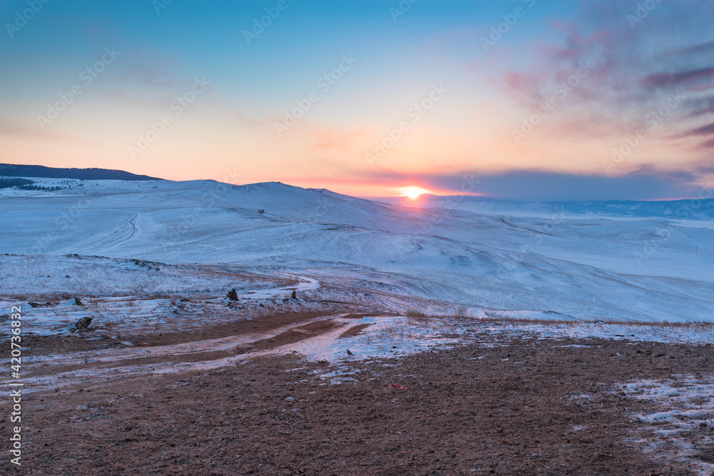 Sunset over the snow-capped mountains of the protected Olkhon island. Lake Baikal, Siberia, Russia Sunset over the snow-capped mountains of the protected Olkhon island. Lake Baikal, Siberia, Russia