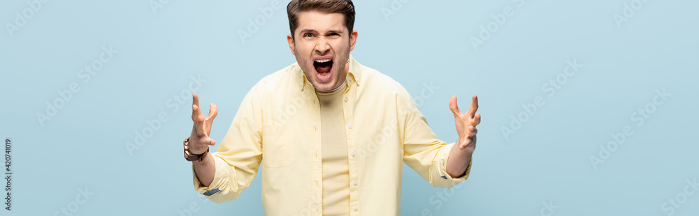angry young man screaming and gesturing isolated on blue, banner angry young man screaming and gesturing isolated on blue, banner