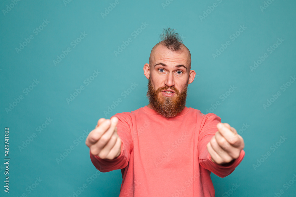 Bearded european man in casual peach isolated on turquoise background rubbing fingers doing money gesture Bearded european man in casual peach isolated on turquoise background rubbing fingers doing money gesture