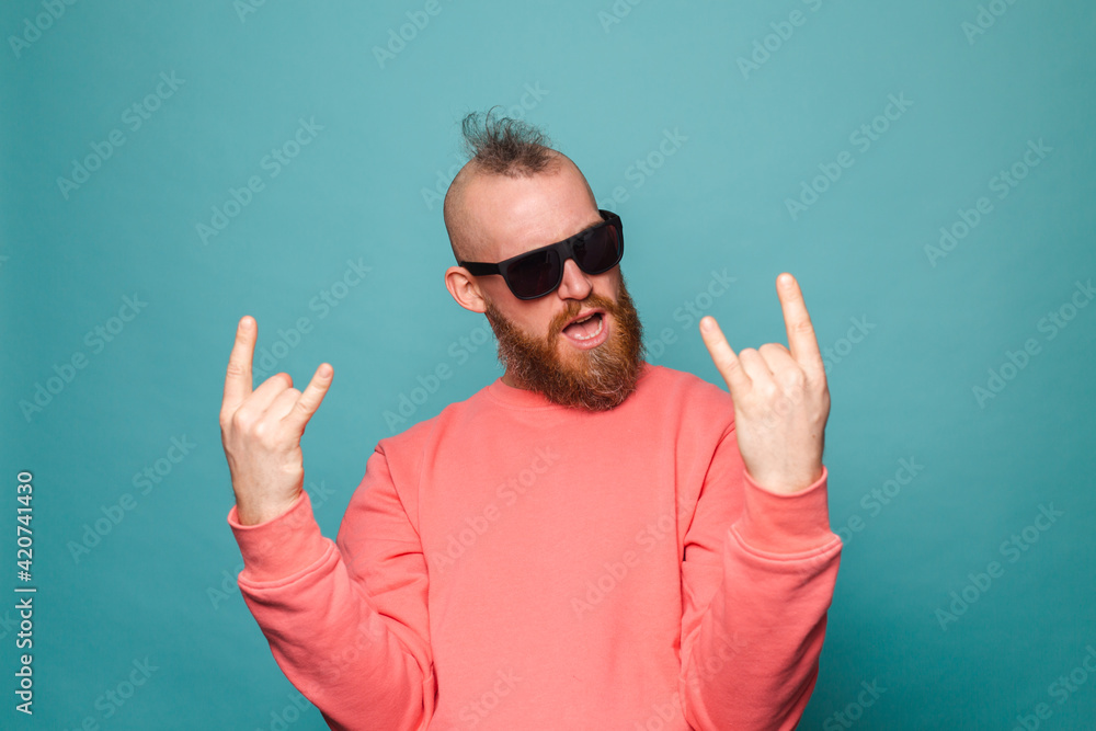 Bearded european man in casual peach isolated on turquoise background shouting with crazy expression doing rock symbol with hands up Bearded european man in casual peach isolated on turquoise background shouting with crazy expression doing rock symbol with hands up