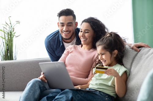 Happy Arabic Family Using Digital Tablet And Credit Card For Online Shopping