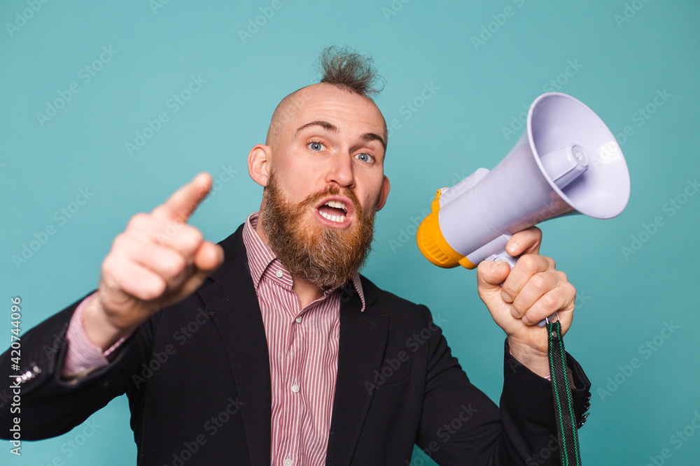 Bearded european businessman in dark suit isolated on turquoise background with megaphone shouting with serious angry face, asking for attention Bearded european businessman in dark suit isolated on turquoise background with megaphone shouting with serious angry face, asking for attention
