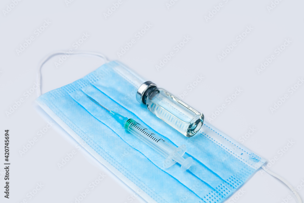 Vaccination kit: syringe, vaccine and mask on a white background. Influenza and coronavirus vaccination. Close-up. Copy space. Vaccination kit: syringe, vaccine and mask on a white background. Influenza and coronavirus vaccination. Close-up. Copy space.