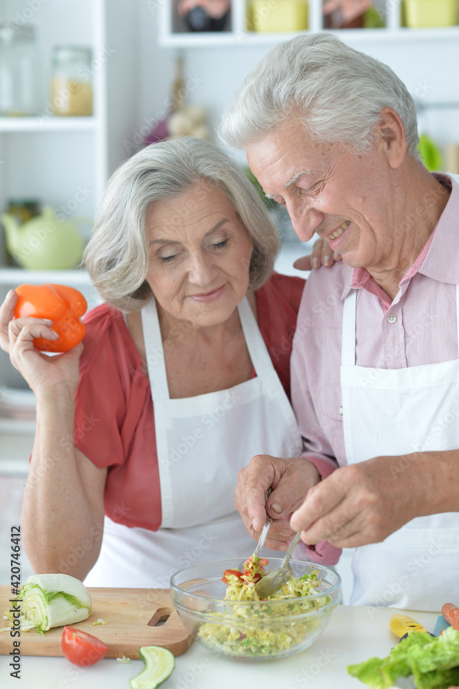 happy senior couple making salad together at kitchen happy senior couple making salad together at kitchen