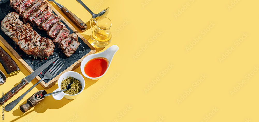 two strip steaks in medium rare fried on a yellow background. dinner concept for two