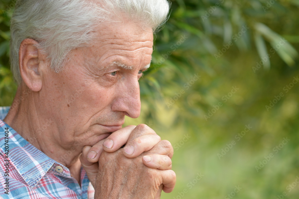 portrait of thinking senior man in park portrait of thinking senior man in park