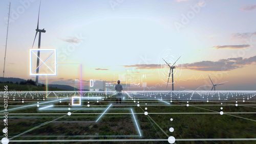 Person in white uniform working on wind farm on sunset using futuristic technology with 3d model construction of windmill buildings. Agronomy business. Tech innovation. Hi-tech concept.Human future