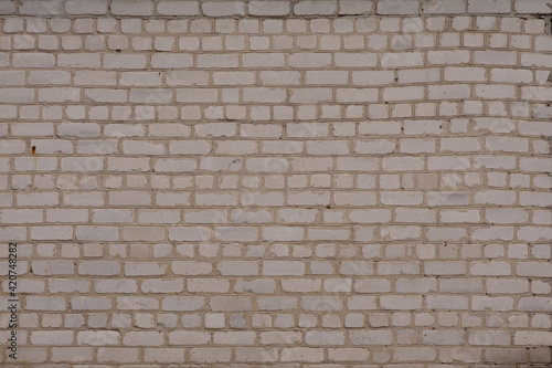 White brick wall. It is laid unevenly. A little darkened with age.