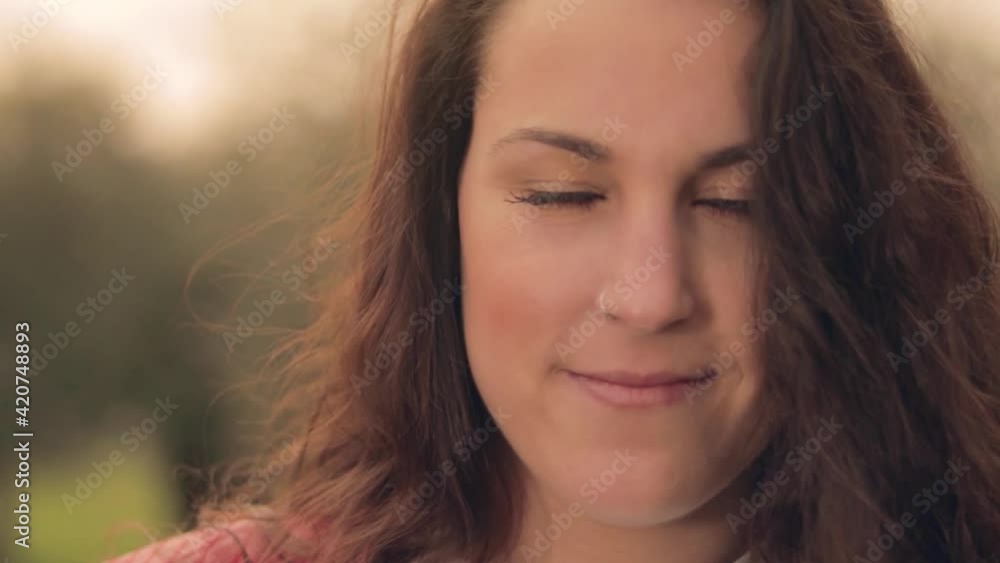 Mujer joven con chaqueta roja sonriendo en un prado verde con olivos y flores amarillas al atardecer Mujer joven con chaqueta roja sonriendo en un prado verde con olivos y flores amarillas al atardecer