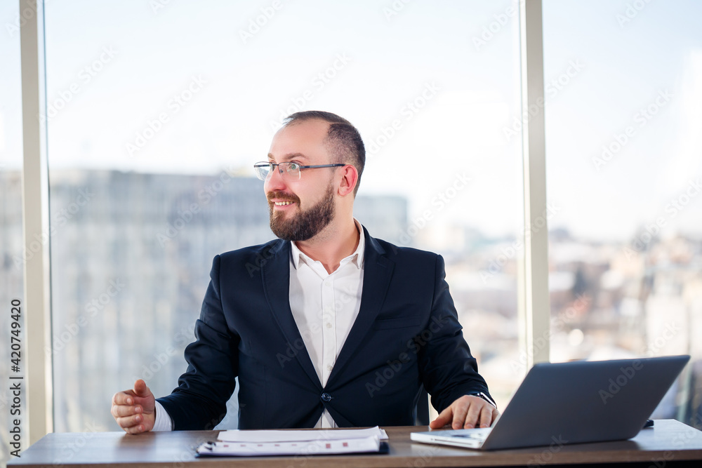 Adult male mentor, director, businessman in glasses and a suit studying documents while sitting at the table. Working day concept Adult male mentor, director, businessman in glasses and a suit studying documents while sitting at the table. Working day concept
