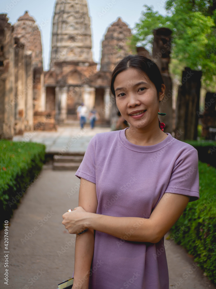 Fototapeta premium Woman wearing purple dress and old temple at Sukhothai, Thailand in March 13 2021