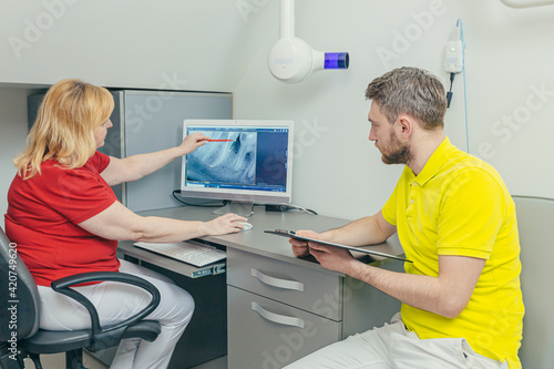 Medical dentist team in dental office discuss and examining x-ray image. looking at computer Desktop screen in modern dental clinic x-ray room In Hospital