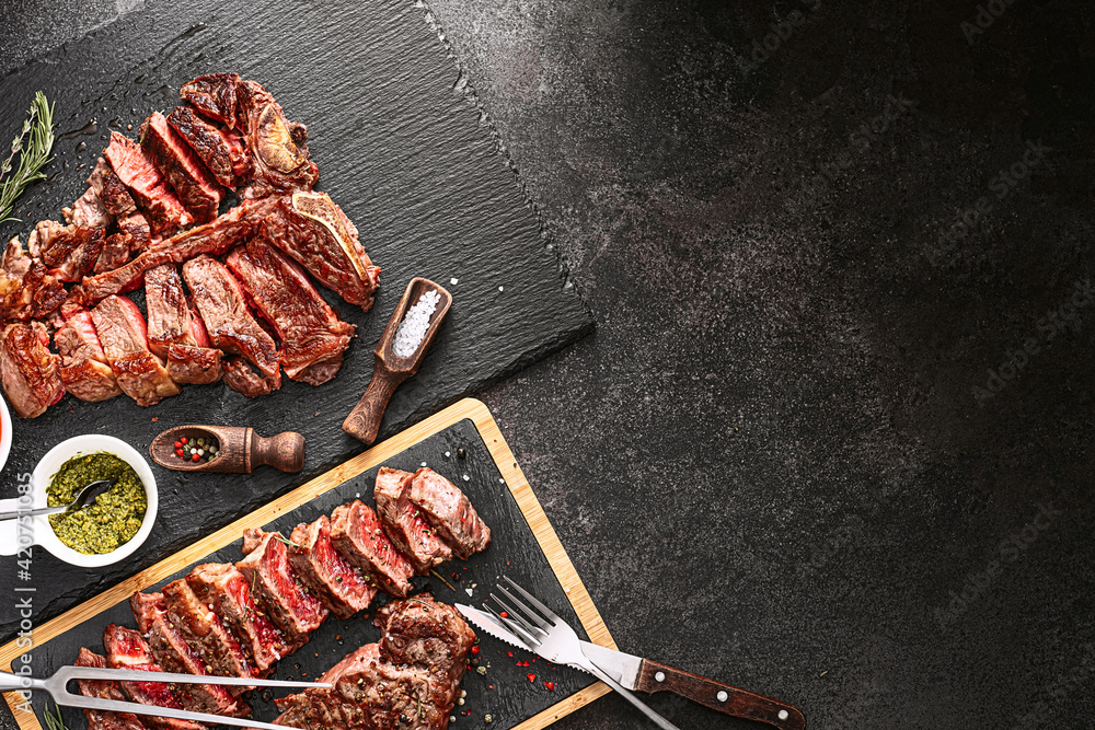 two steaks striploin and t-bon, medium rare, on a stone background. dinner concept for two