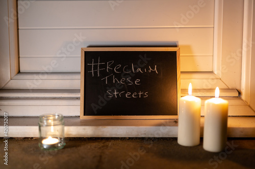 Fototapeta Naklejka Na Ścianę i Meble -  A chalkboard with reclaim the streets on the doorstep of a house with a small tea light and 2 pillar candles to show solidarity