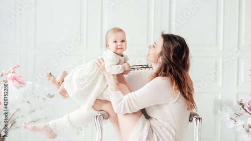womens or mother day. Happy beautiful young 38 years mother with baby girl in arms. concept of happy family, motherhood. Woman playing with child girl in room.