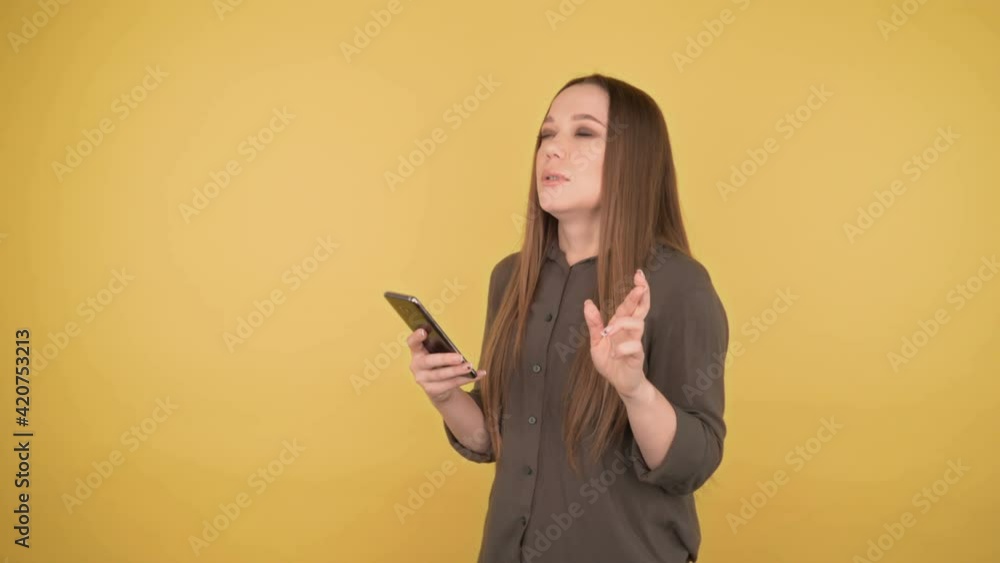 I won. Shocked joyful business woman crosser fingers on a swell on an isolated yellow background with looking looks at the smartphone I won. Shocked joyful business woman crosser fingers on a swell on an isolated yellow background with looking looks at the smartphone
