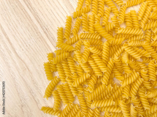Food background or texture raw dry Italian pasta in shape of spiral on wooden table or desk. Closeup, macro, top view. Uncooked macaroni.