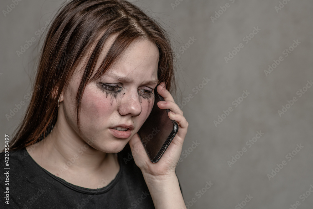 Crying teen girl talking to using a mobile phone. Empty space for text Crying teen girl talking to using a mobile phone. Empty space for text