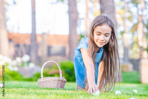 Happy young girl hunts for Easter eggs on green grass © Ermolaev Alexandr