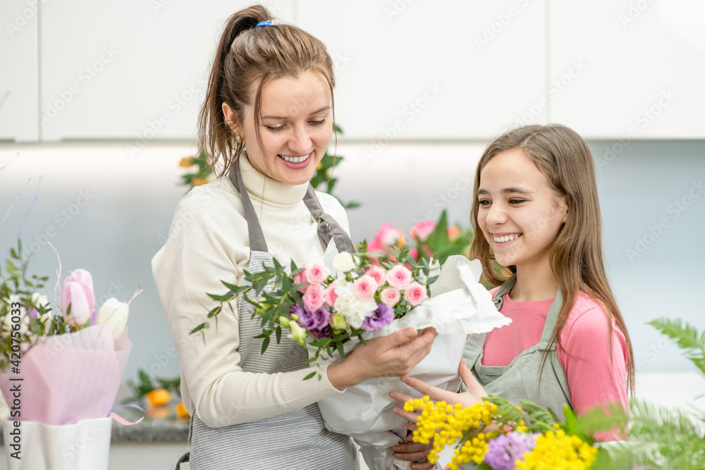 Woman teaches to young girl arranging flower