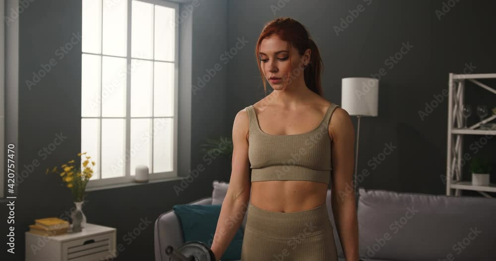 Strong muscular woman doing workout at home to stay fit. Athletic lady wearing sports clothes training hands lifting dumbbells. Strong muscular woman doing workout at home to stay fit. Athletic lady wearing sports clothes training hands lifting dumbbells.