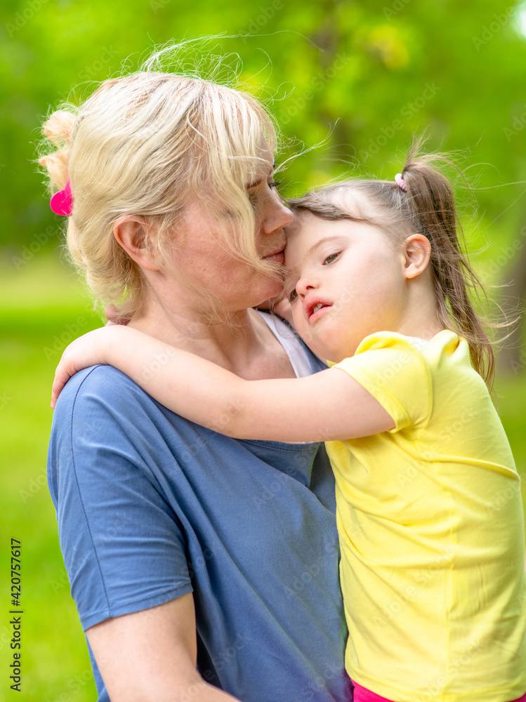 Mother and little girl with syndrom down have a fun in summer park Mother and little girl with syndrom down have a fun in summer park