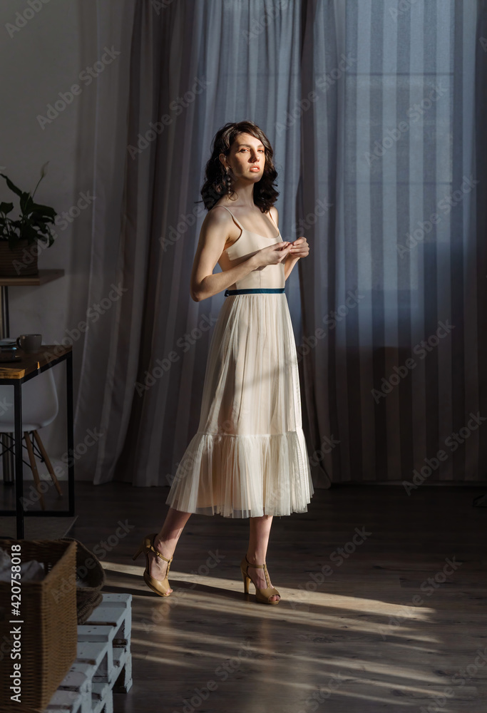 Cute young girl stands in the studio on the background of curtains. Stylish fashionable designer clothes.