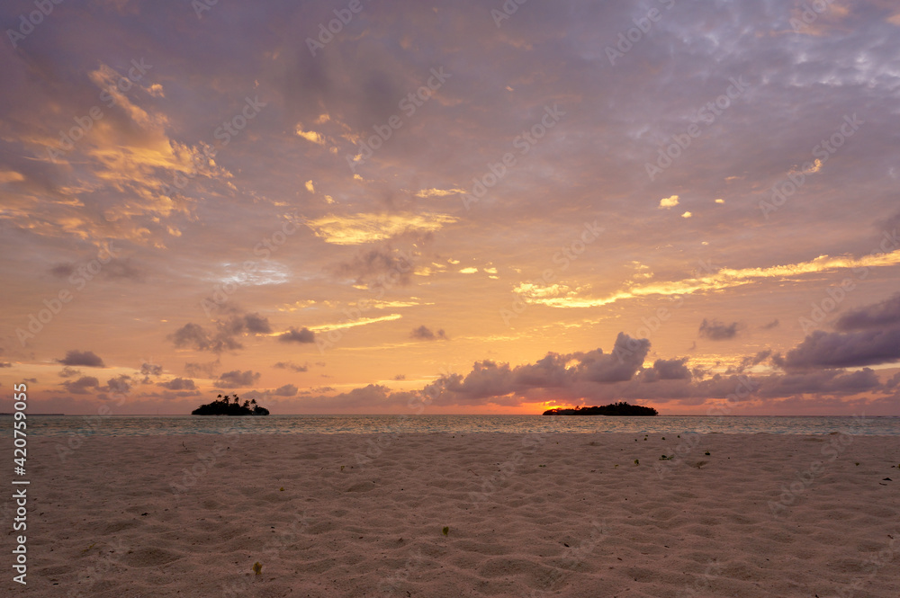 Sunrise with dramatic clouds on the tropical beach. Panorama with two uninhabited tropical islands