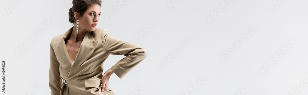 sensual brunette woman looking away while posing with hand on hip isolated on grey, banner - obrazy, fototapety, plakaty 